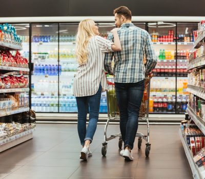 Back view of a smiling couple walking with a trolley at the supermarket